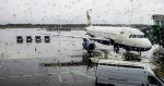 A white plane is on the ground at the airport and there are raindrops on the camera lens, indicating bad weather.